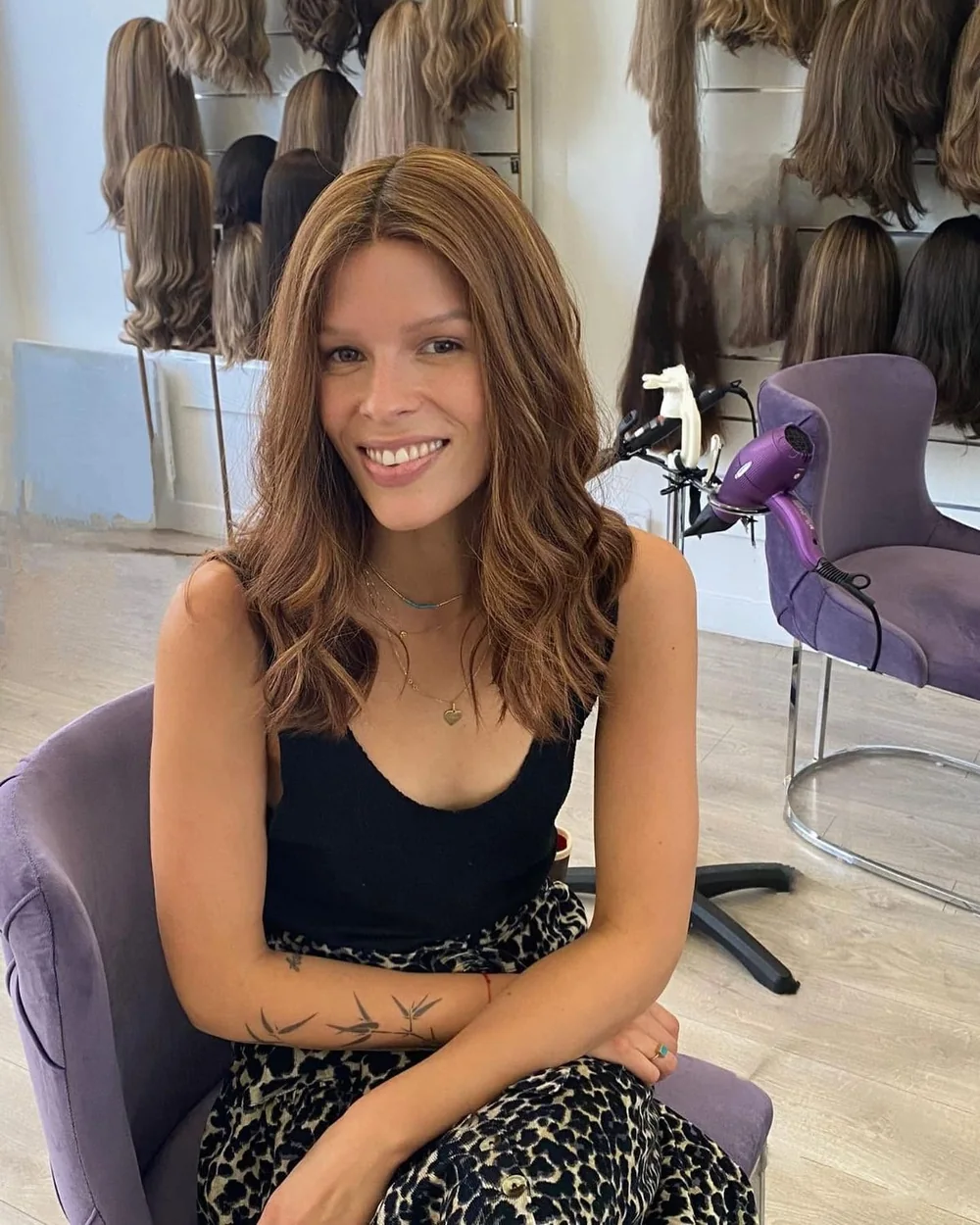 Cliente souriante portant une perruque en cheveux naturels dans le salon Dvora C Wigs à Levallois-Perret