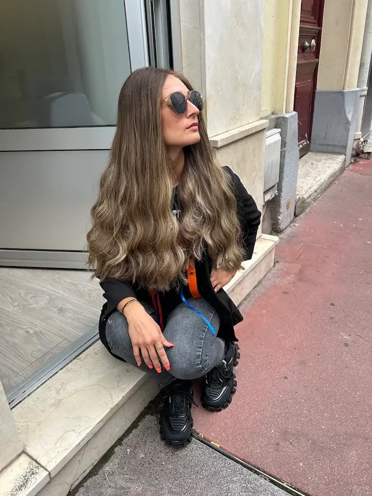 Cliente aux longs cheveux ondulés, perruque naturelle Dvora C Wigs, devant le salon de Levallois-Perret