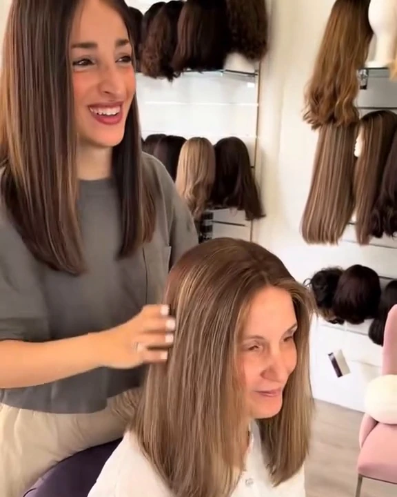 Dvora Chemouni, souriante, coiffe une cliente dans son salon de perruques Dvora C Wigs à Levallois-Perret